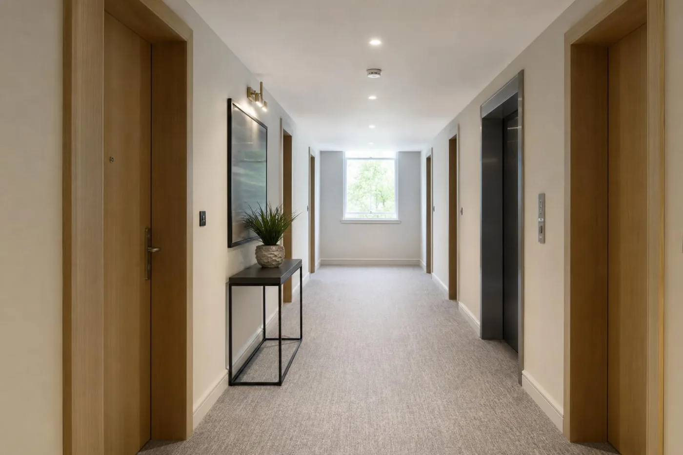 Clean apartment building corridor with timber doors, a lift lobby and daylight from an end window.