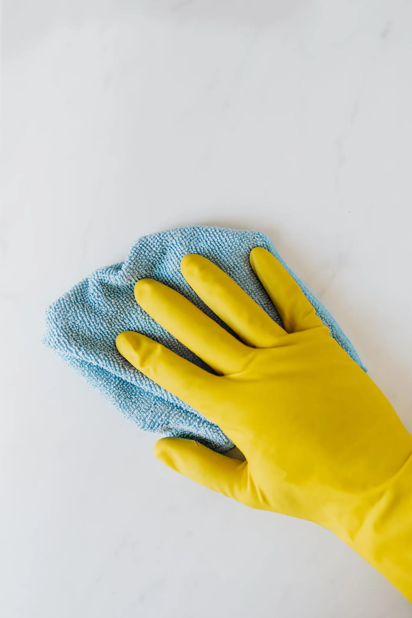Gloved hand wiping a white surface with a cloth.